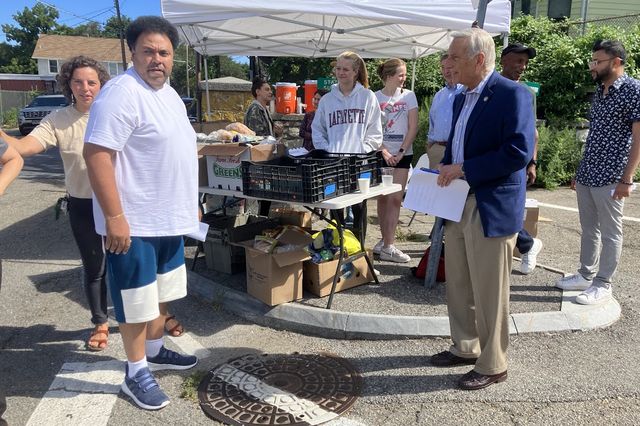 Activist Wilfredo Laracuente speaks with Queens  Assemblymember David Weprin in front of the farm stand, as other volunteers look on.